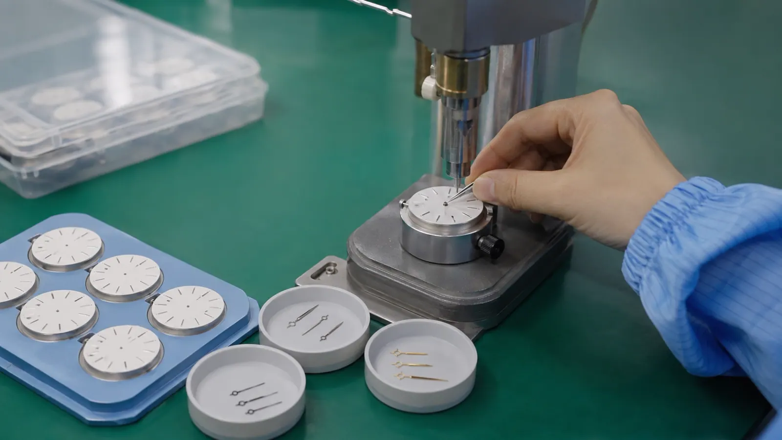 Technician fitting hands onto a watch movement